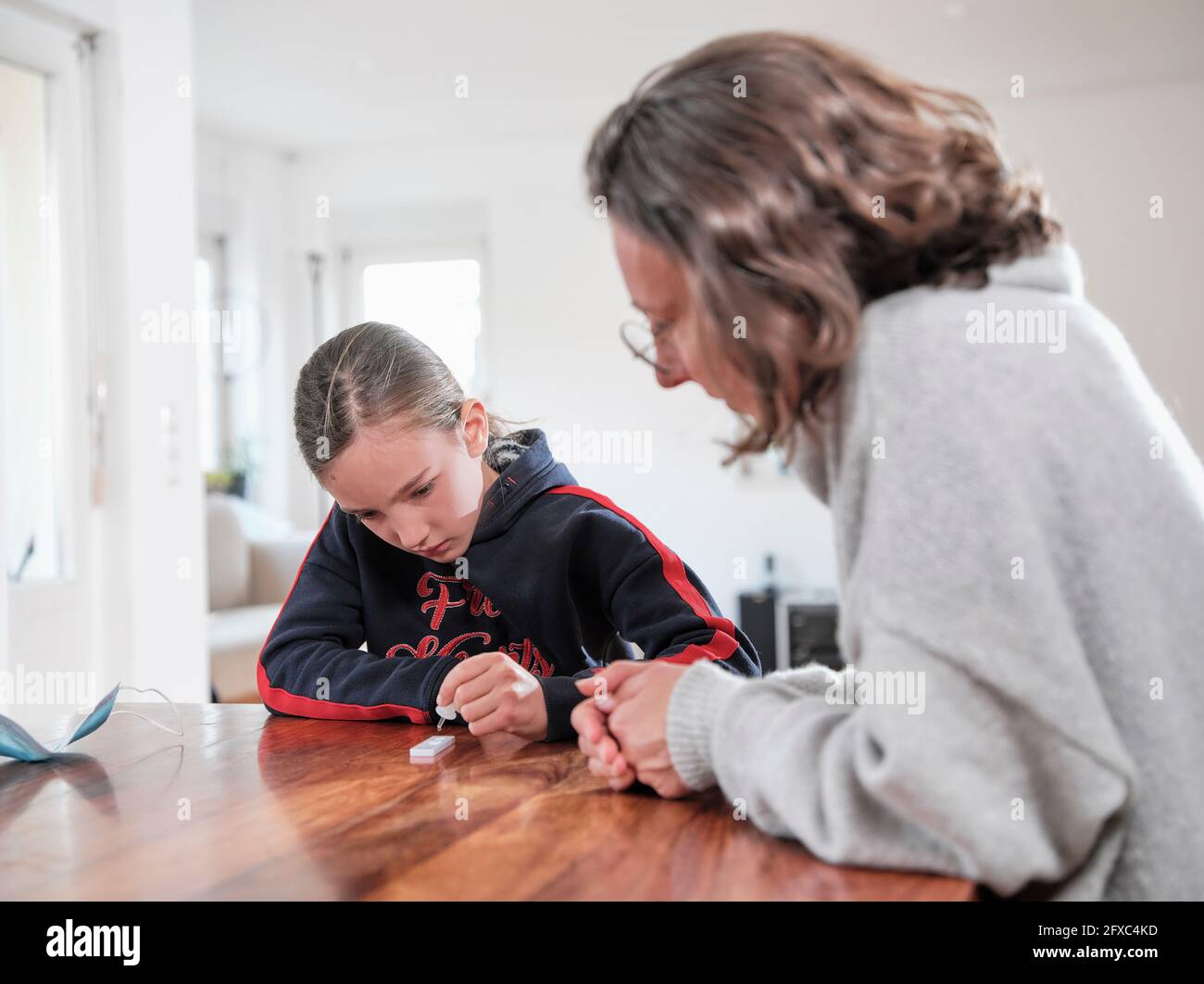 Mother looking at daughter examining medical test at home Stock Photo