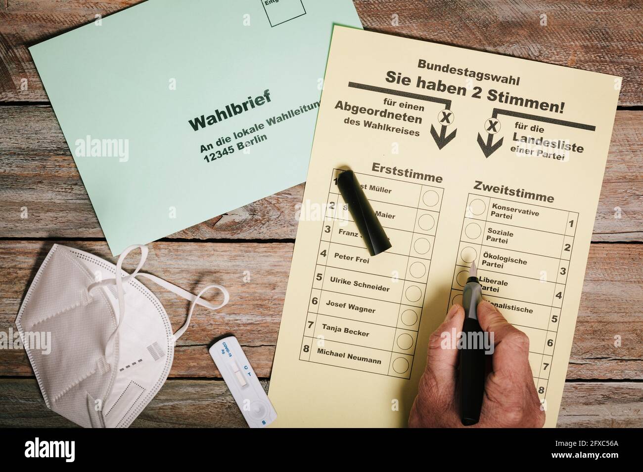 Hand checking ballot for federal elections by mail on table with protective mask and corona rapid test Stock Photo