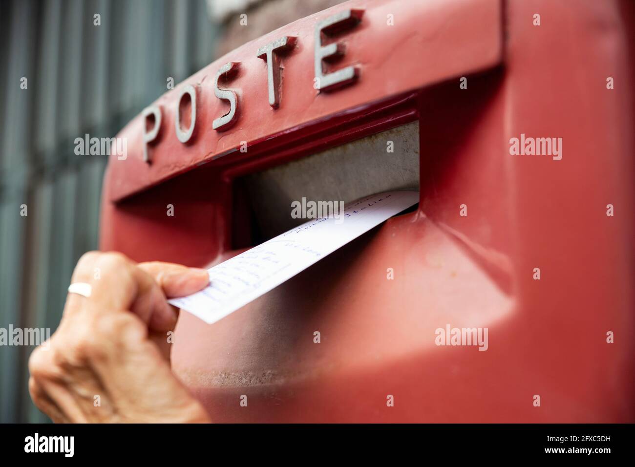 Woman dropping envelope in postbox Stock Photo