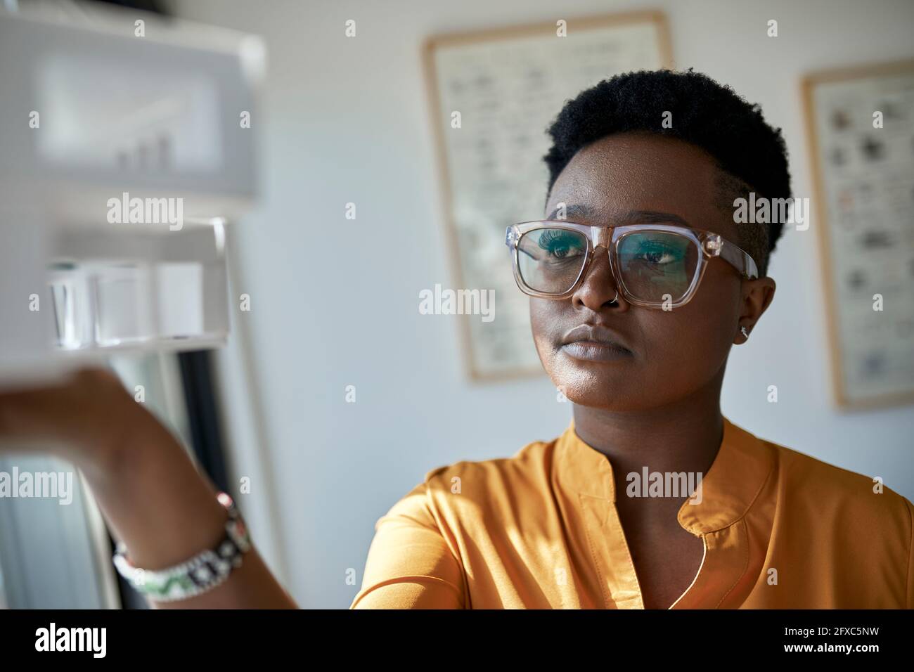 Female architect wearing eyeglasses holding model at office Stock Photo