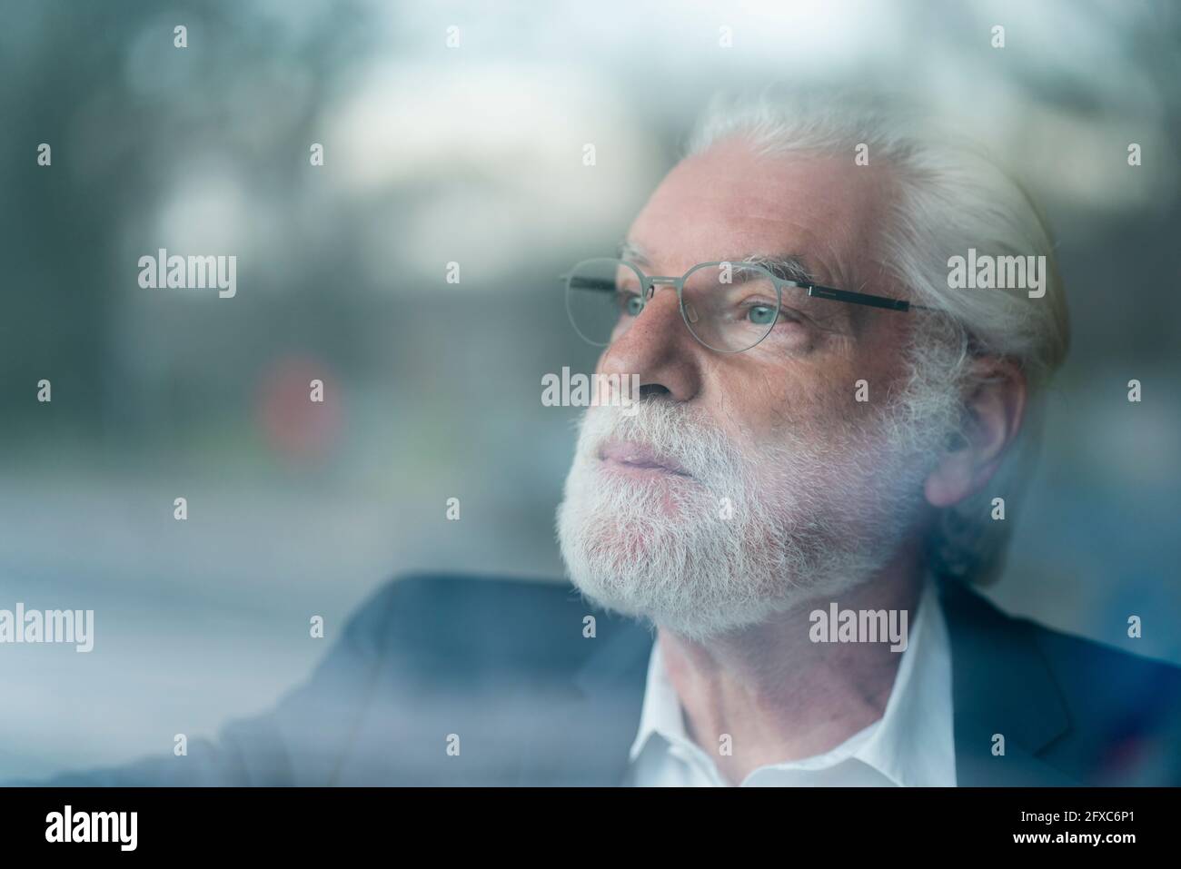 Senior businessman with gray eyes looking through window seen through glass Stock Photo