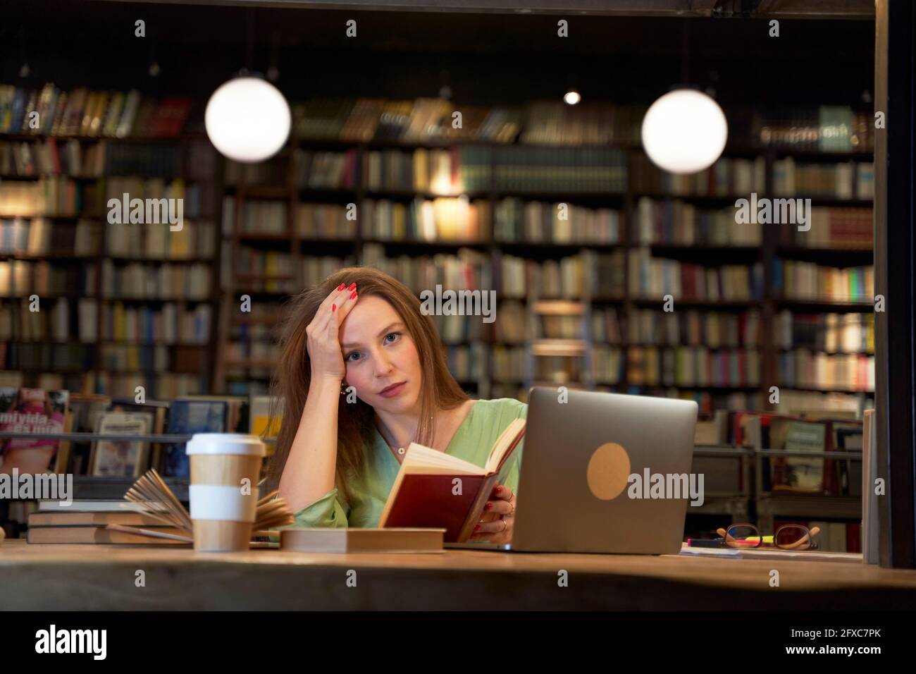 Female student holding book in library Stock Photo - Alamy