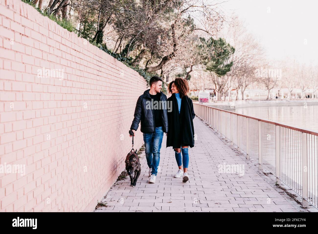 Young couple walking with dog on footpath Stock Photo