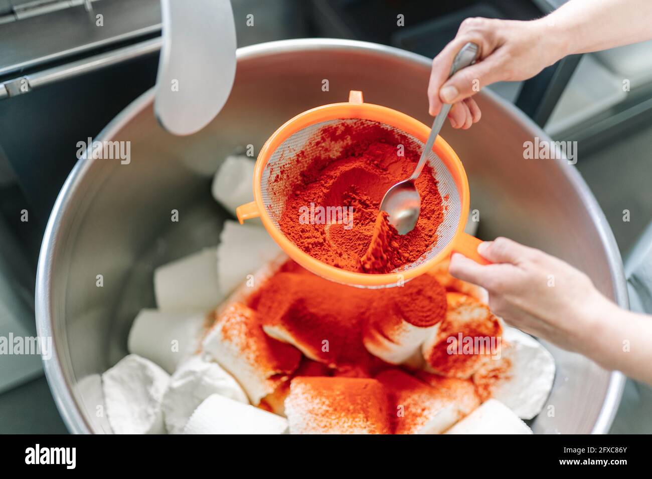 Woman putting red ingredient through strainer in container Stock Photo