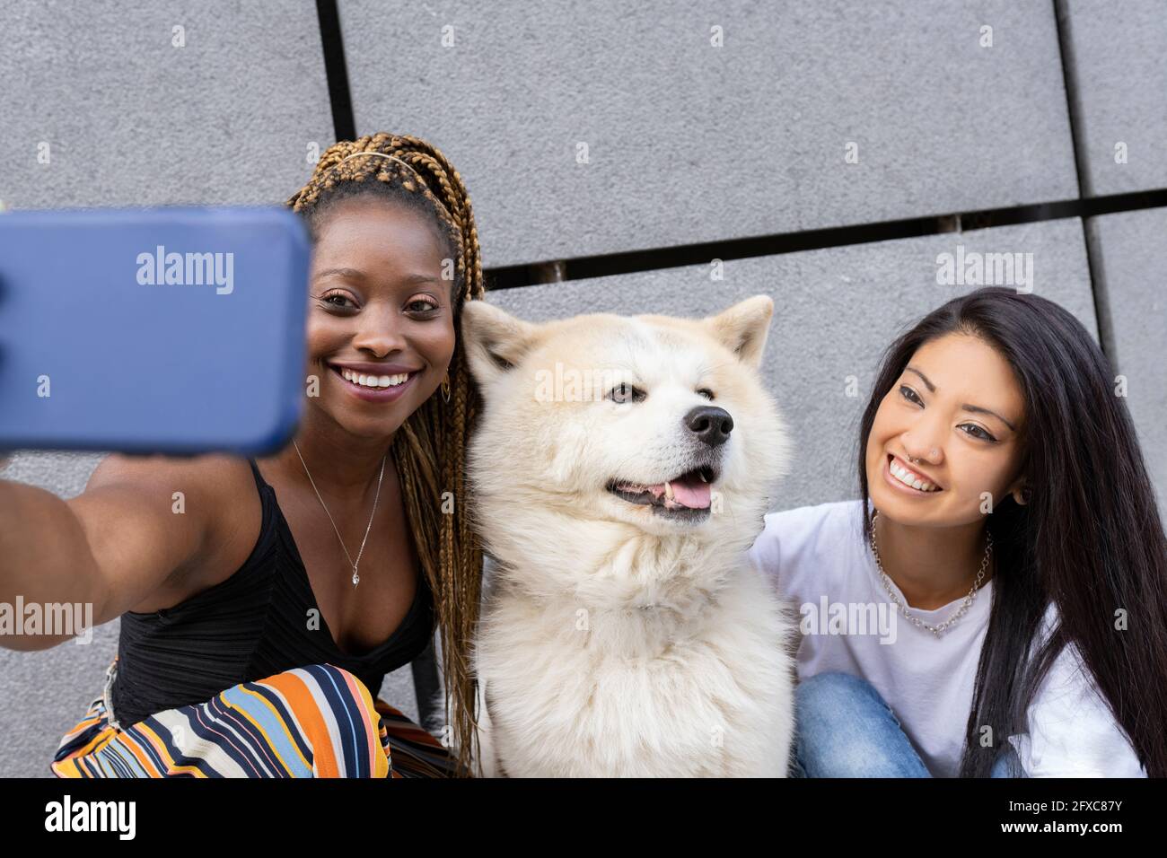 Multi-ethnic female friends taking selfie with dog outdoors Stock Photo