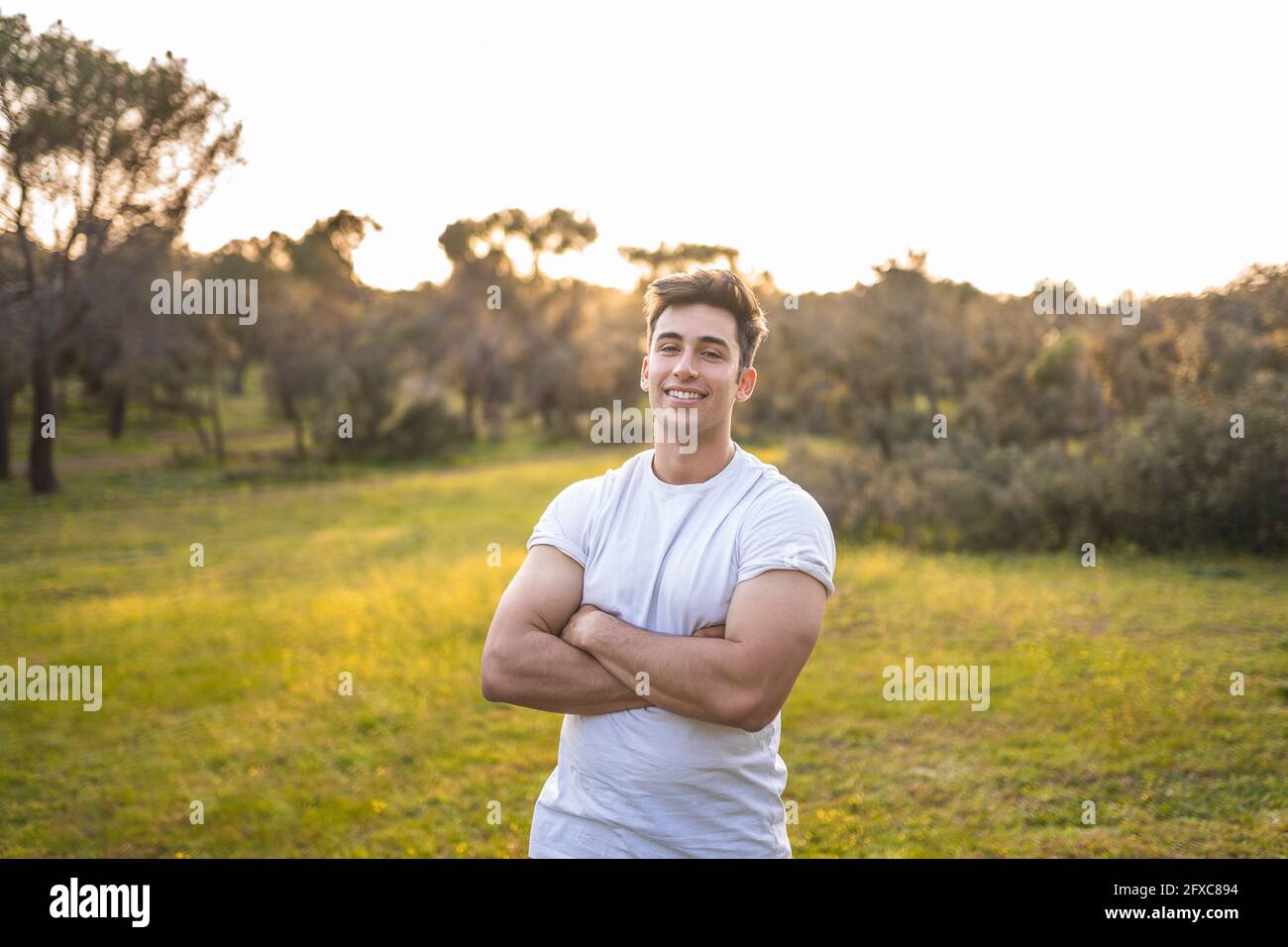 Handsome sports person standing with arms crossed during sunset Stock Photo