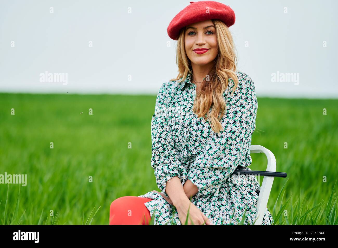 Beautiful woman wearing red beret while sitting at meadow Stock Photo