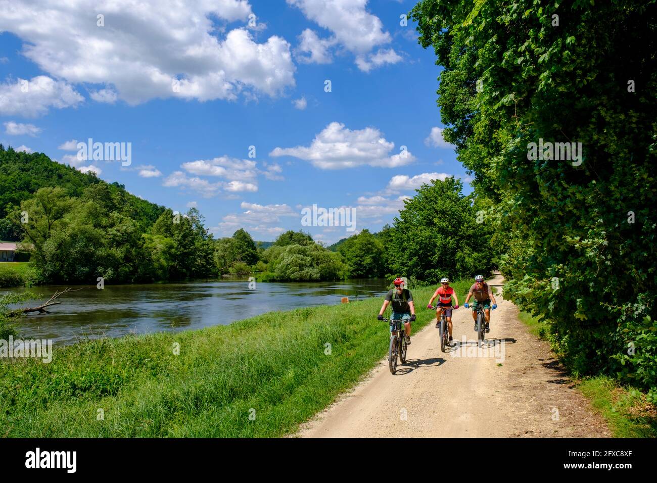 Germany, Bavaria, Duggendorf, Three mature adults cycling along bank of Naab river Stock Photo
