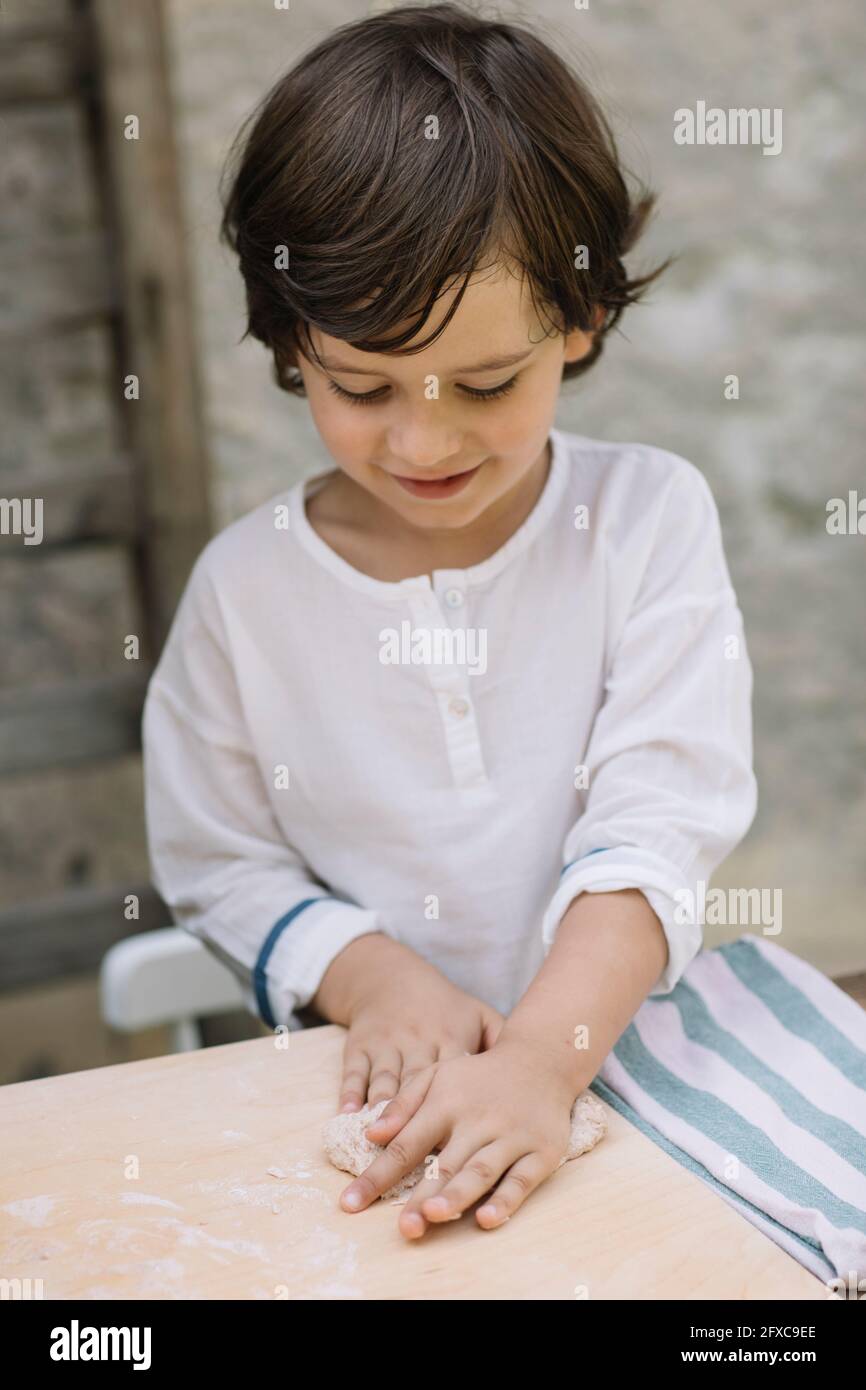 Cute boy playing with dough at backyard Stock Photo