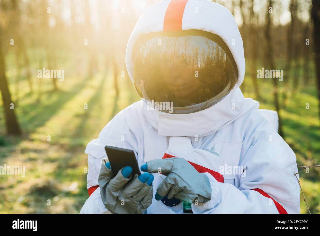 Young astronaut wearing space suit and helmet using mobile phone in ...