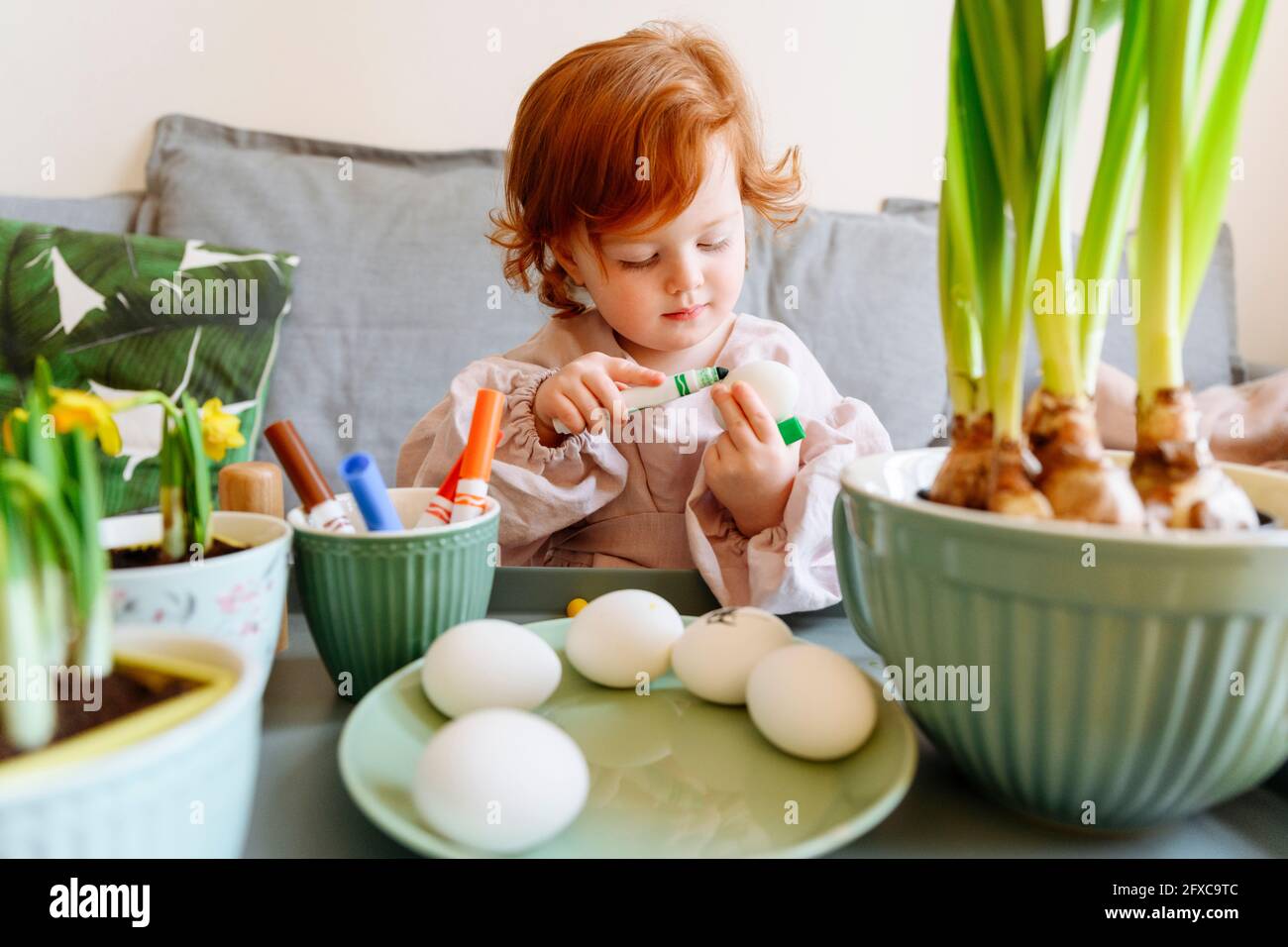 Girl coloring egg during Easter at home Stock Photo