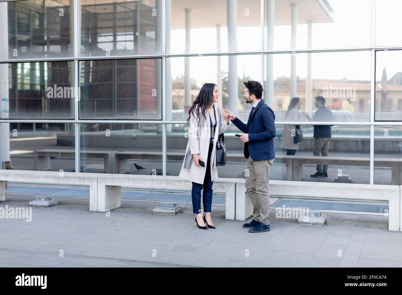 Business couple talking while standing on footpath Stock Photo