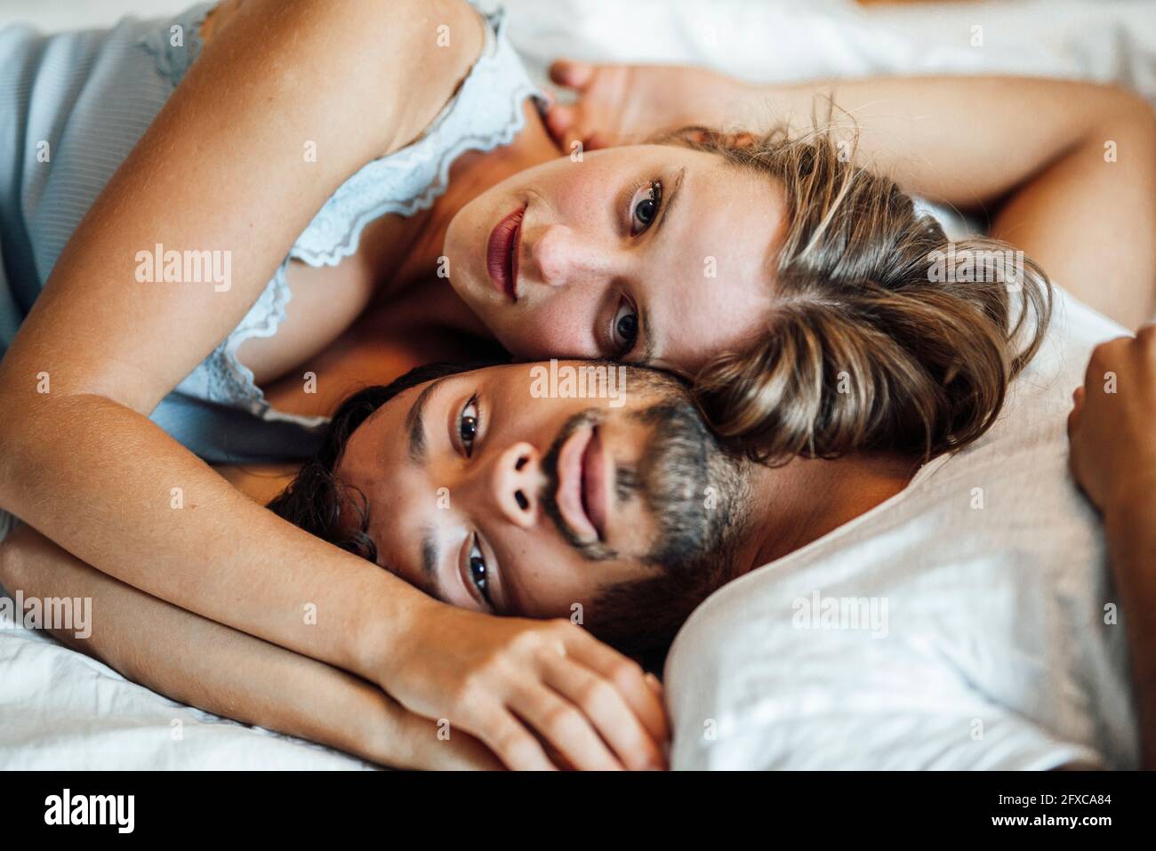Romantic young couple lying on bed at home Stock Photo