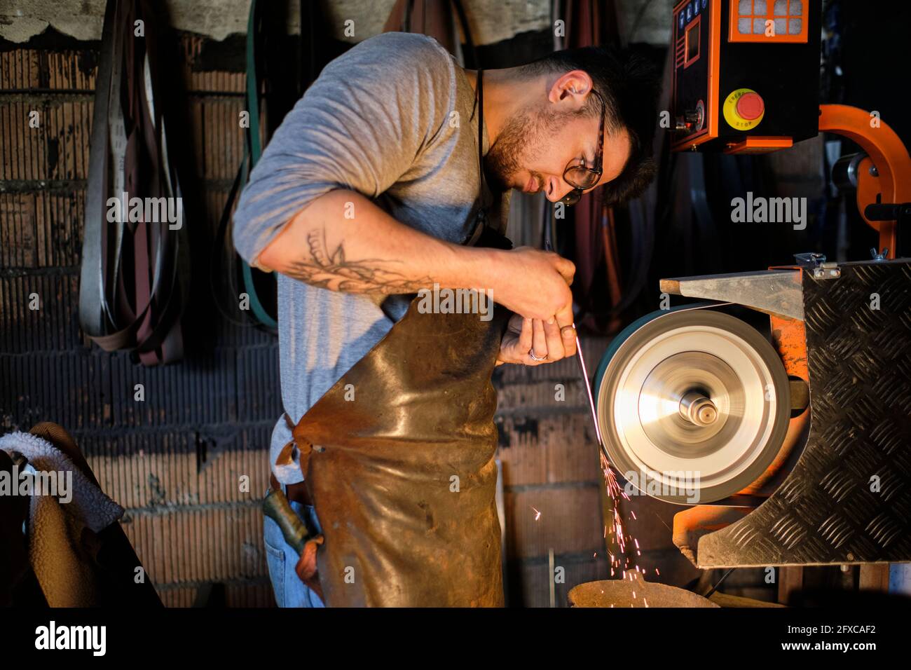 Craftsman sharpening metal on grinder at Stock Photo Alamy