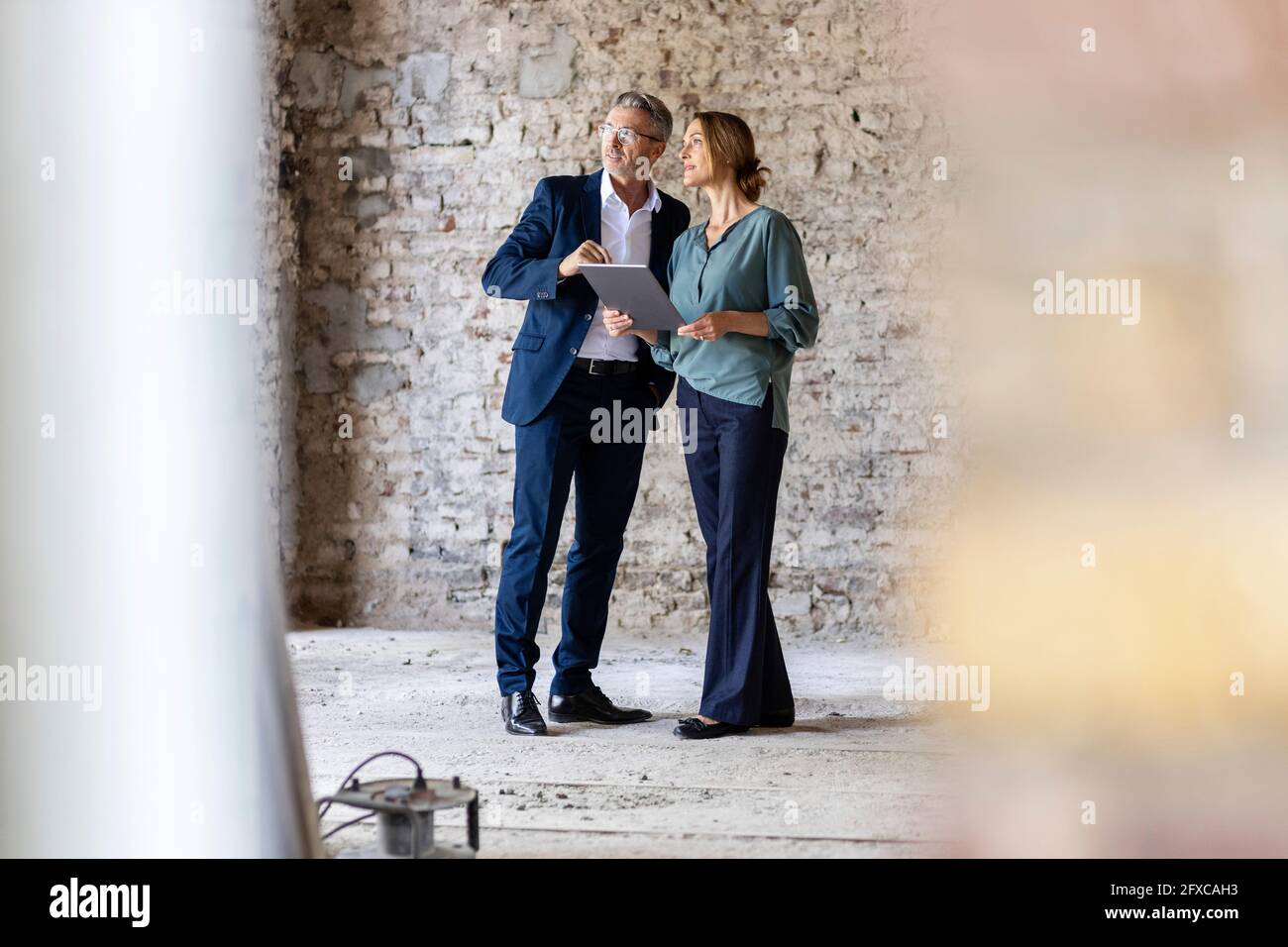 Male and female architects discussing while standing at construction site Stock Photo