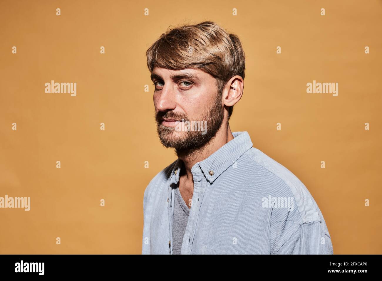 Man looking with sideways glance by wall Stock Photo