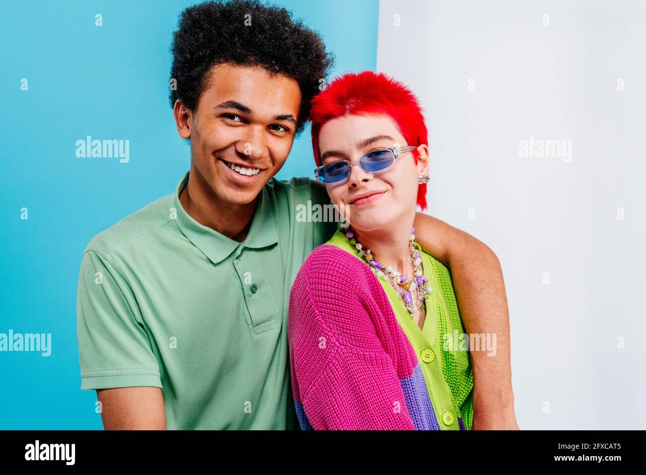 Smiling redhead woman with hand on shoulder of male friend on blue and white background Stock Photo