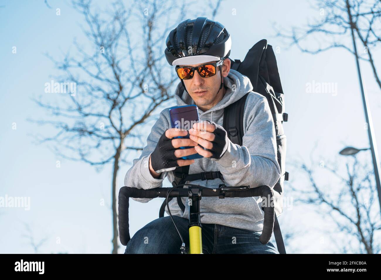 Delivery man leaning on bicycle while using smart phone Stock Photo