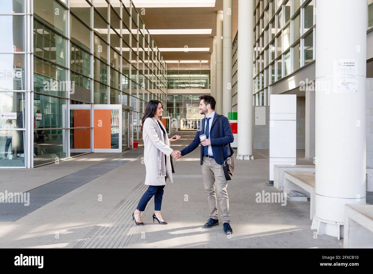 Business people greeting through handshake while standing on footpath Stock Photo