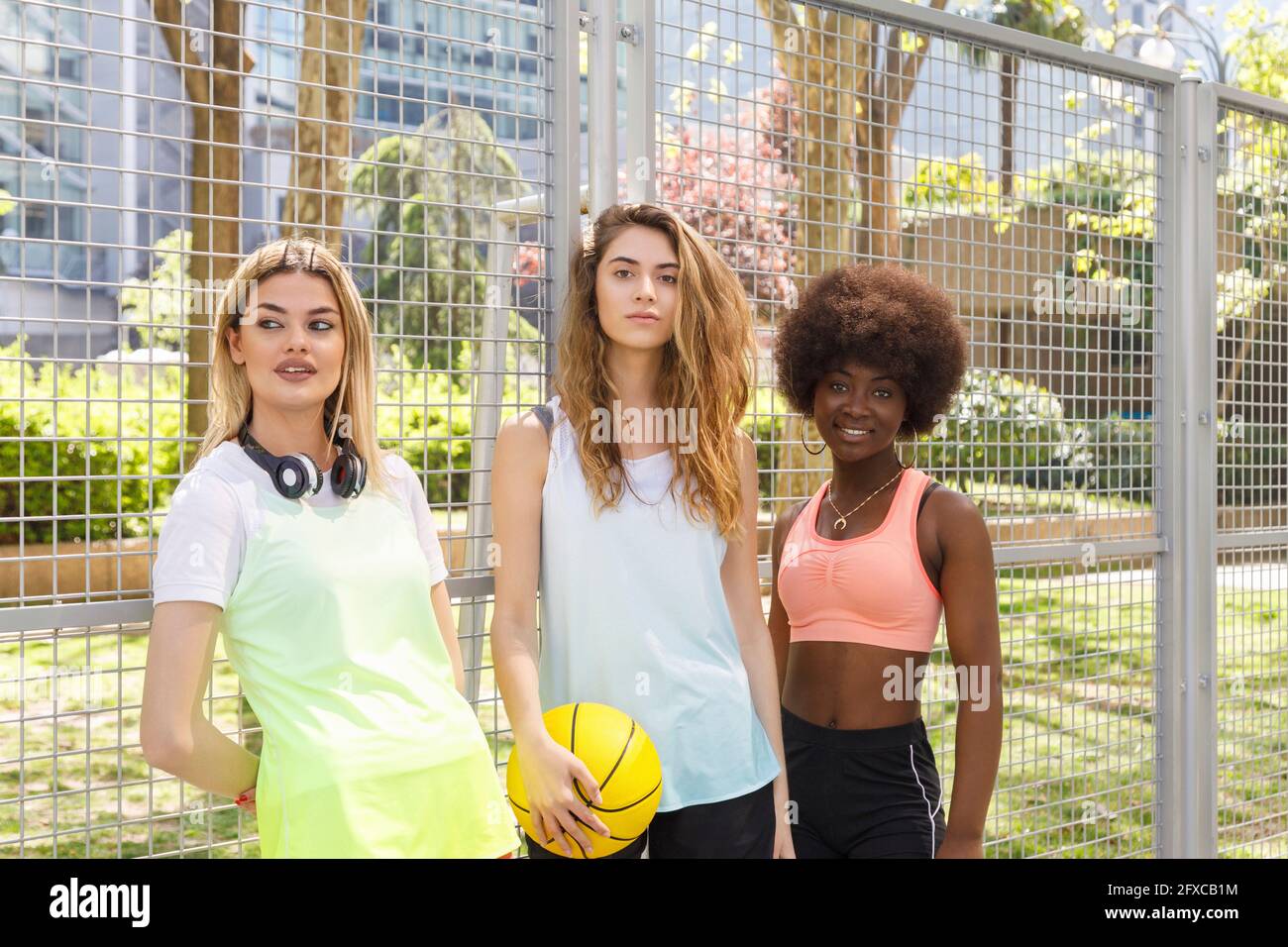 Young women standing by park fence Stock Photo