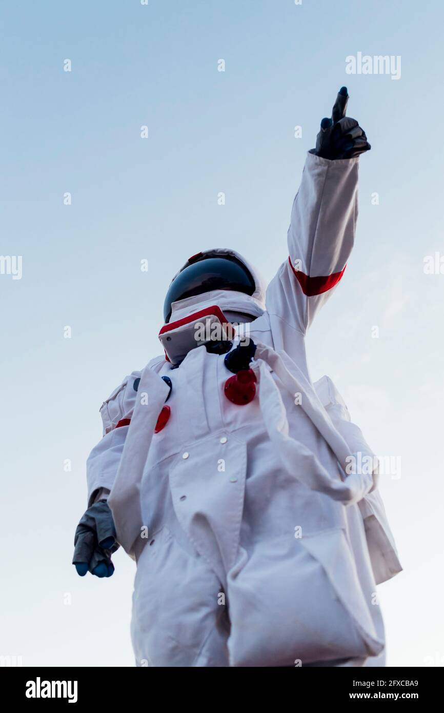 Young female astronaut pointing while wearing space suit Stock Photo
