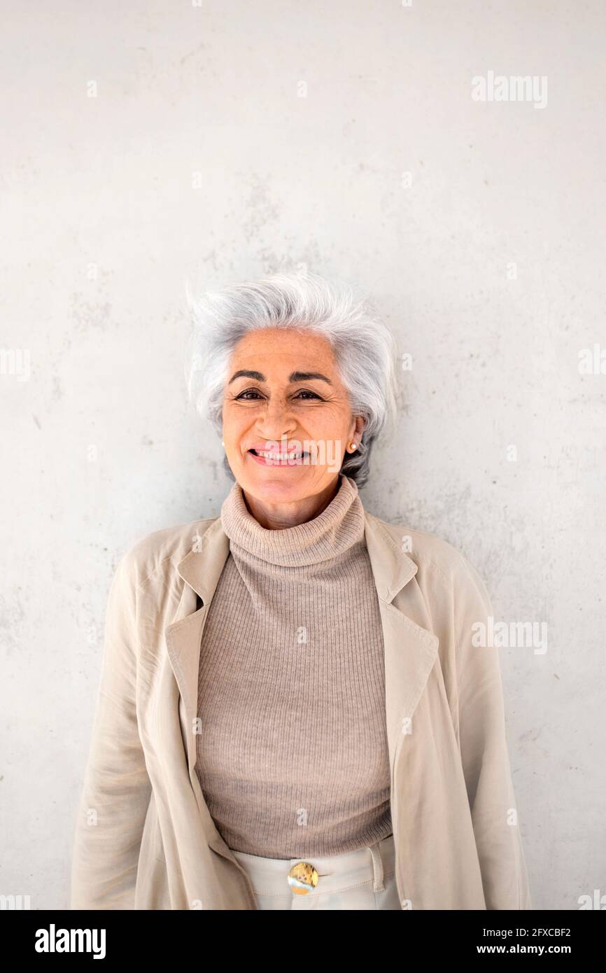 Minimal waist up portrait of smiling mature woman wearing neutral