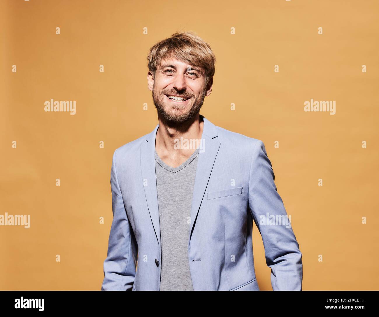 Happy man standing in front of yellow wall Stock Photo - Alamy