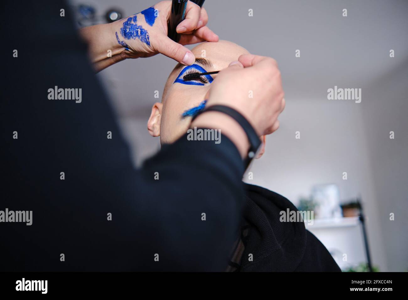 Make-up artist applying mascara on male model's eyelash at studio Stock Photo