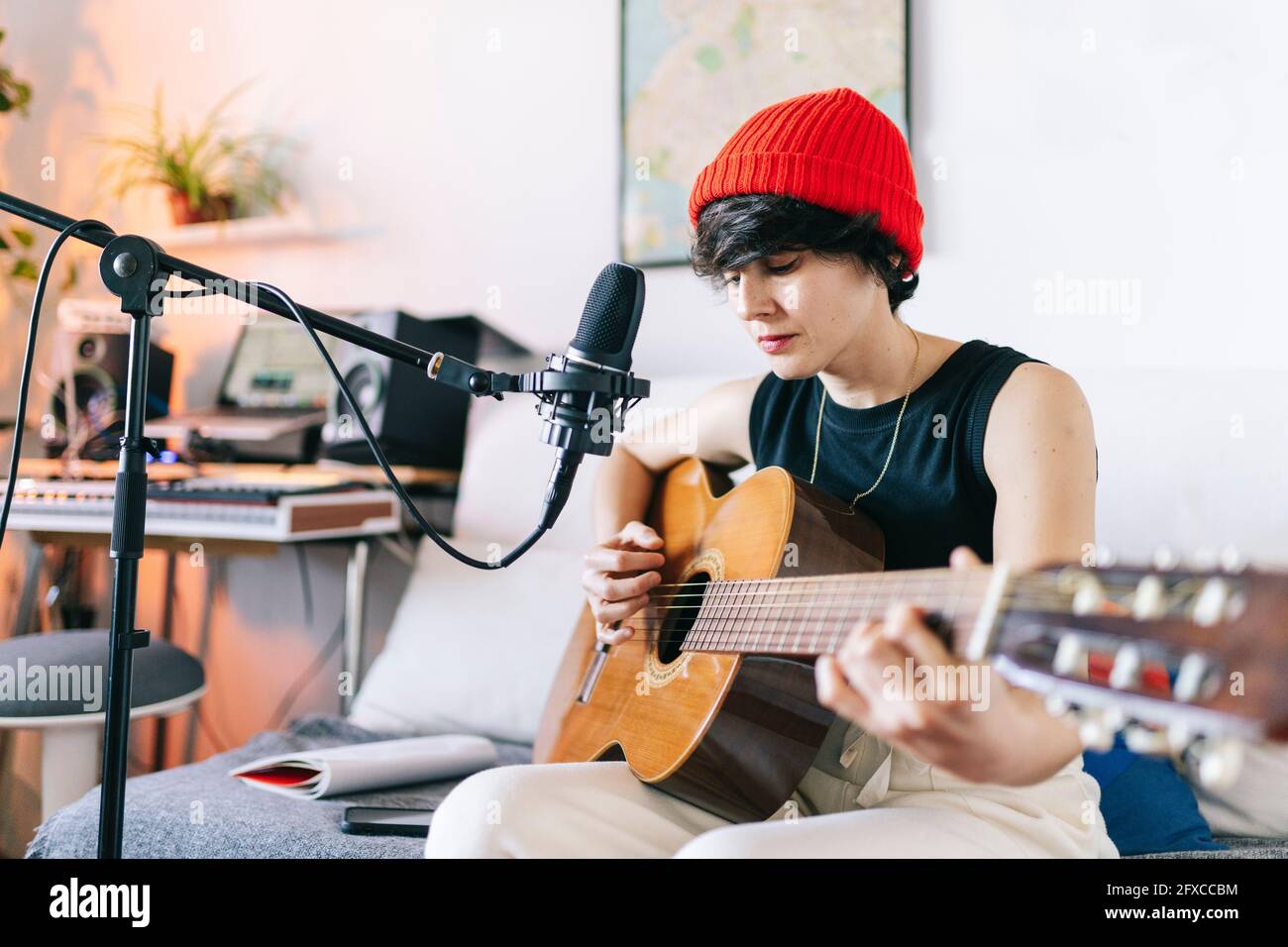 Female guitarist wearing knit hat while playing guitar at studio Stock Photo