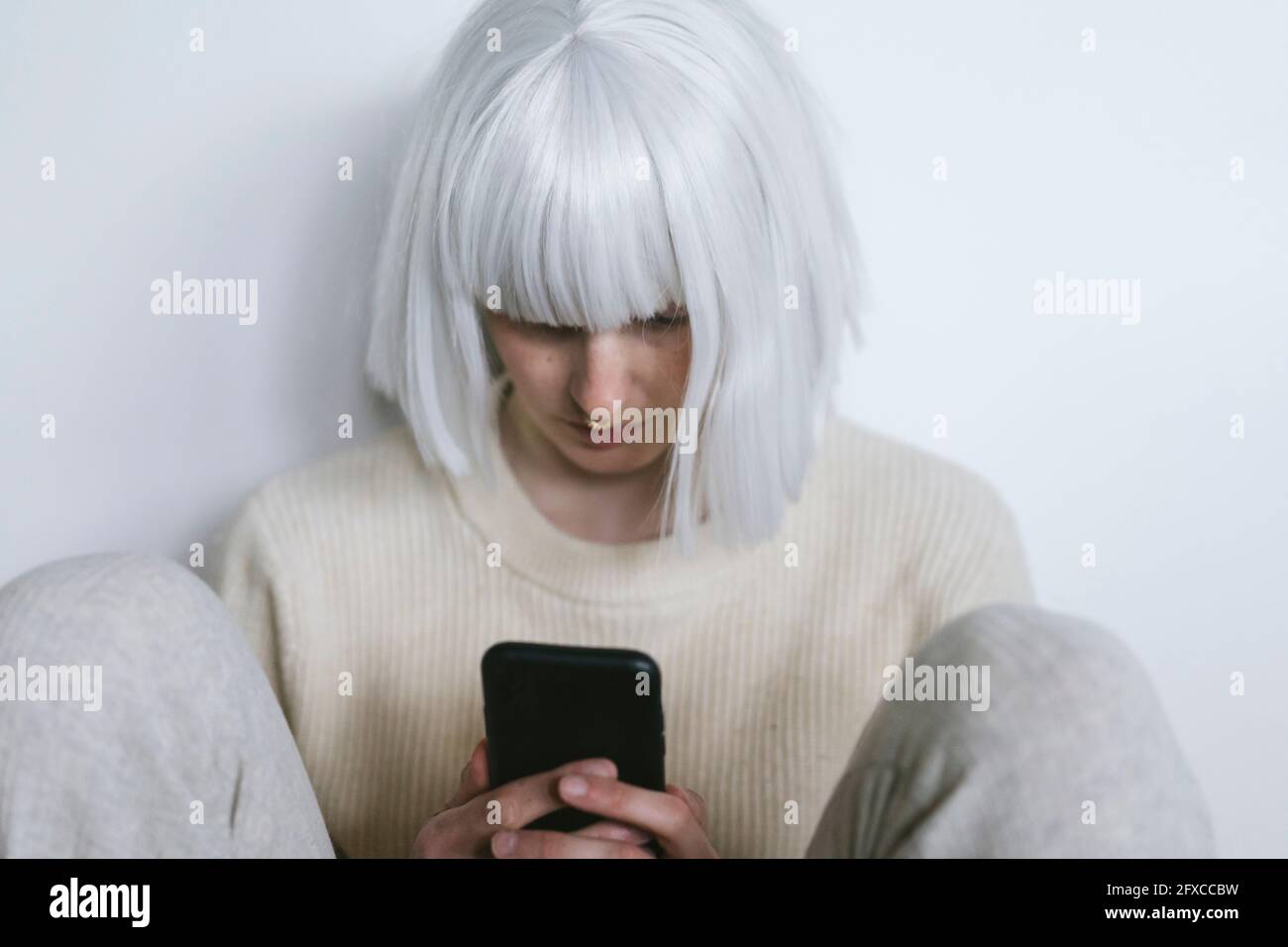 Mid adult woman with bangs using mobile phone Stock Photo