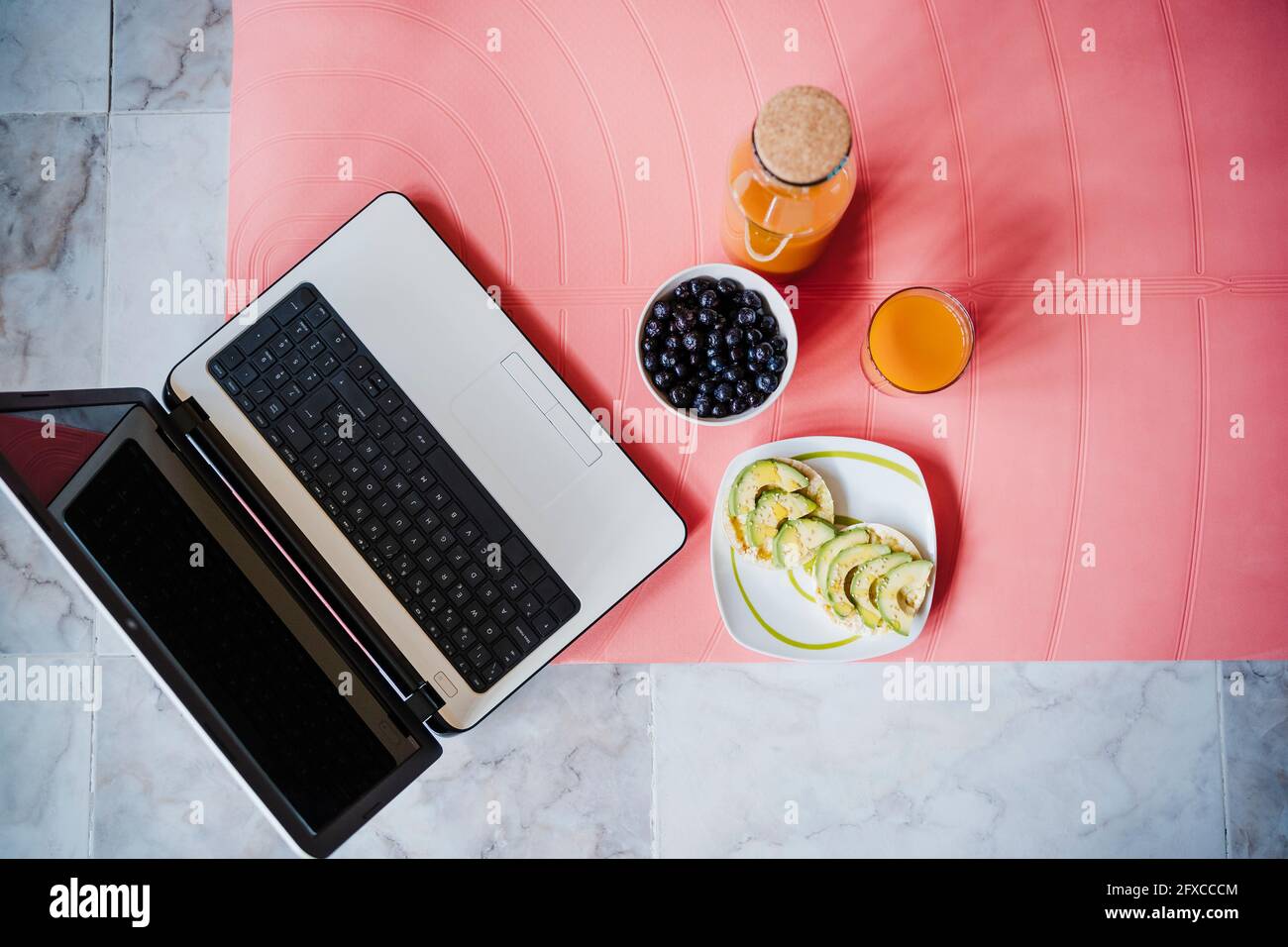 Laptop and healthy breakfast on exercise mat at home Stock Photo