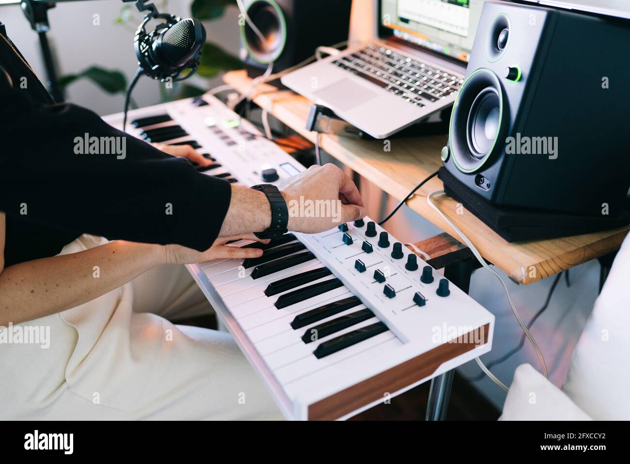 Male and female musicians working on electric piano in studio Stock