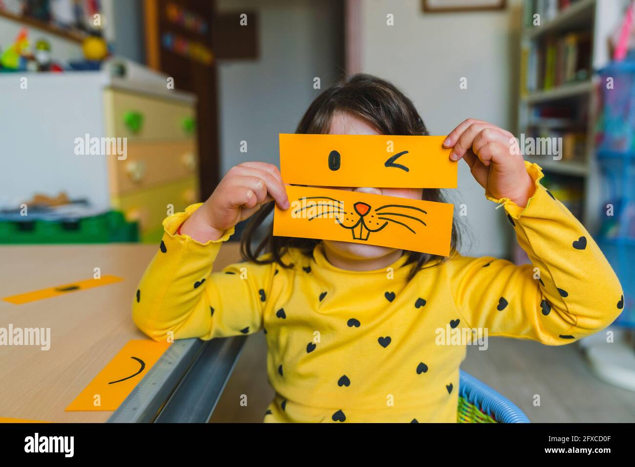 Girl holding animal and winking emoticon over face while playing at