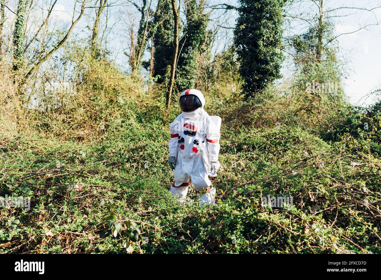 Young astronaut wearing space suit and helmet standing in bush at ...