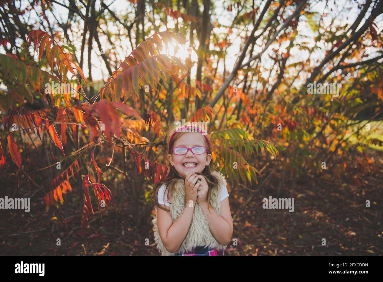 Smiling girl wearing eyeglasses in front of plants during autumn Stock Photo