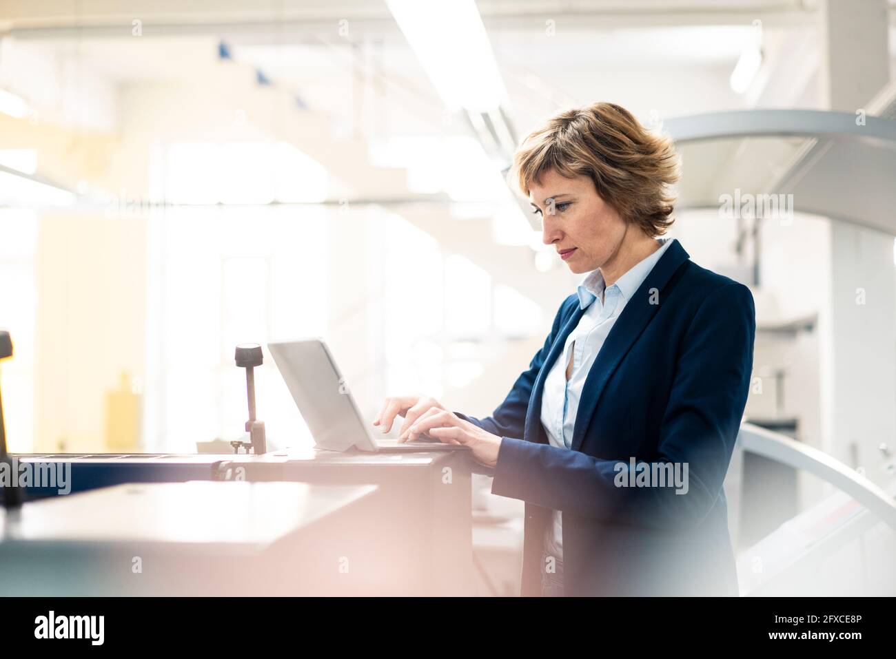 Mature female entrepreneur using laptop while working at industry Stock Photo