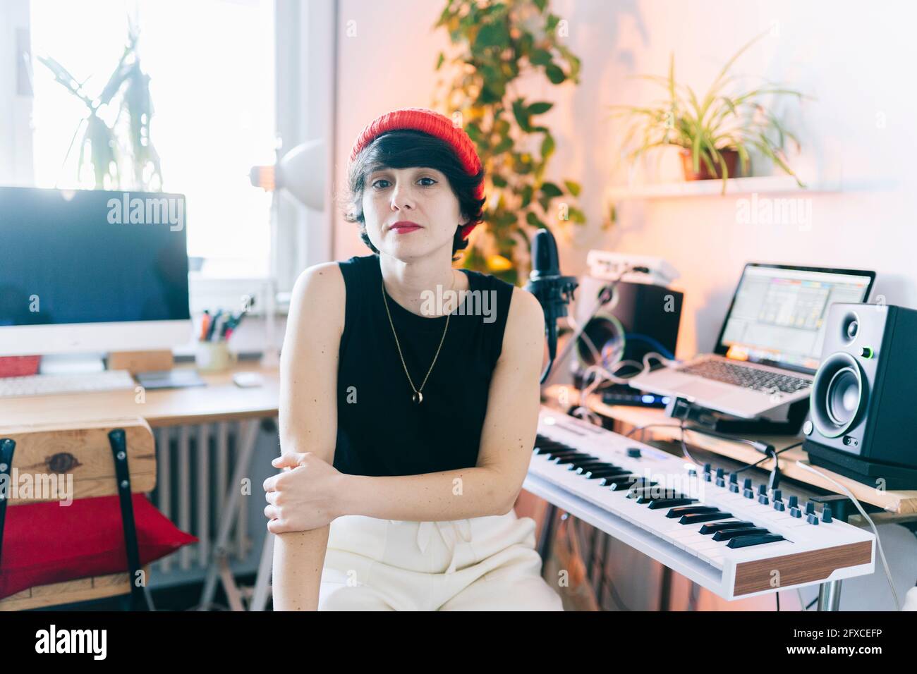 Female music composer wearing knit hat while sitting by electric piano