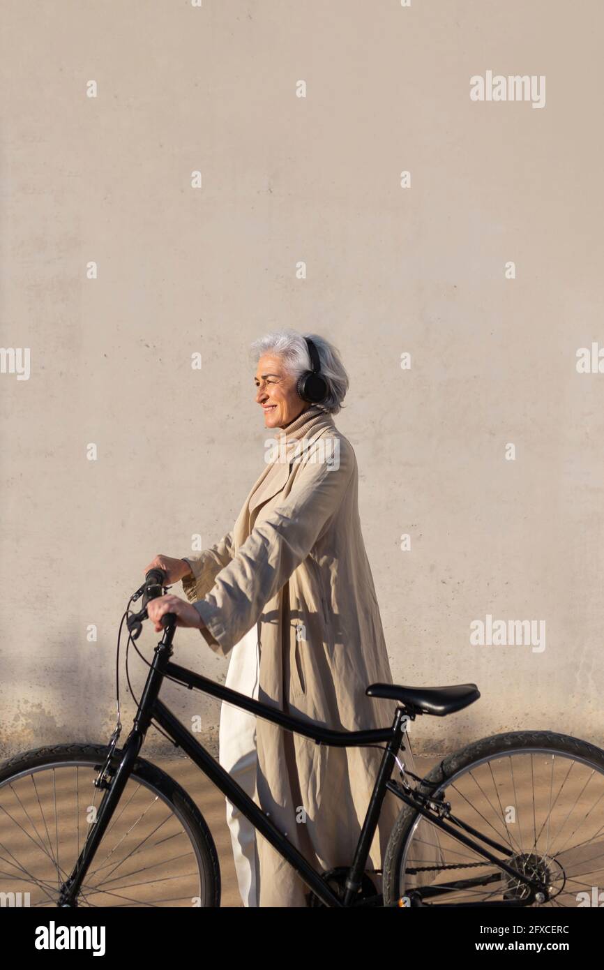 Smiling woman looking away while standing with bicycle Stock Photo