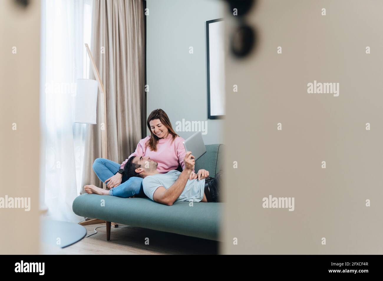 Smiling woman looking at man lying on lap in hotel room Stock Photo