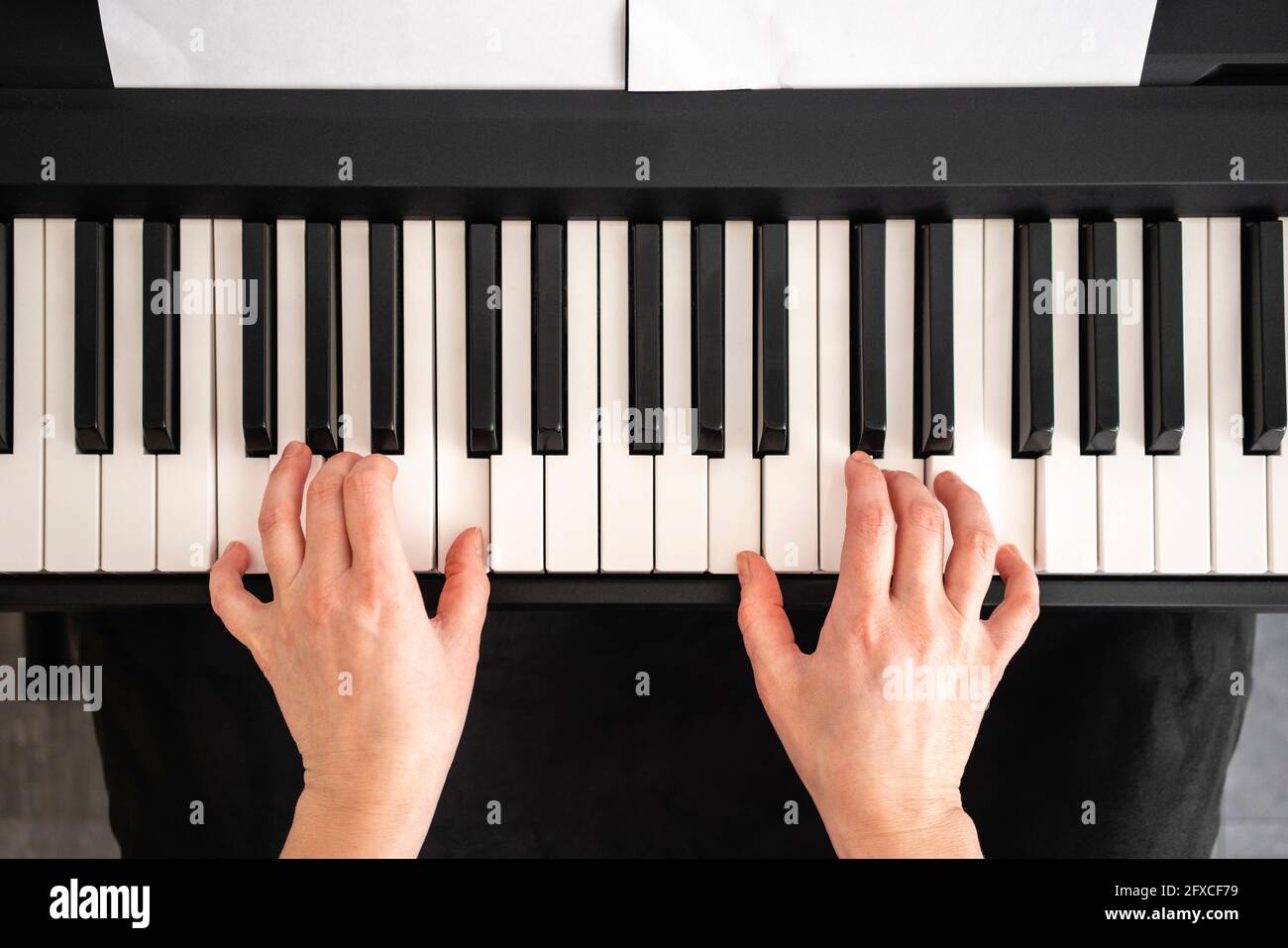 Mid adult woman playing piano notes at home Stock Photo