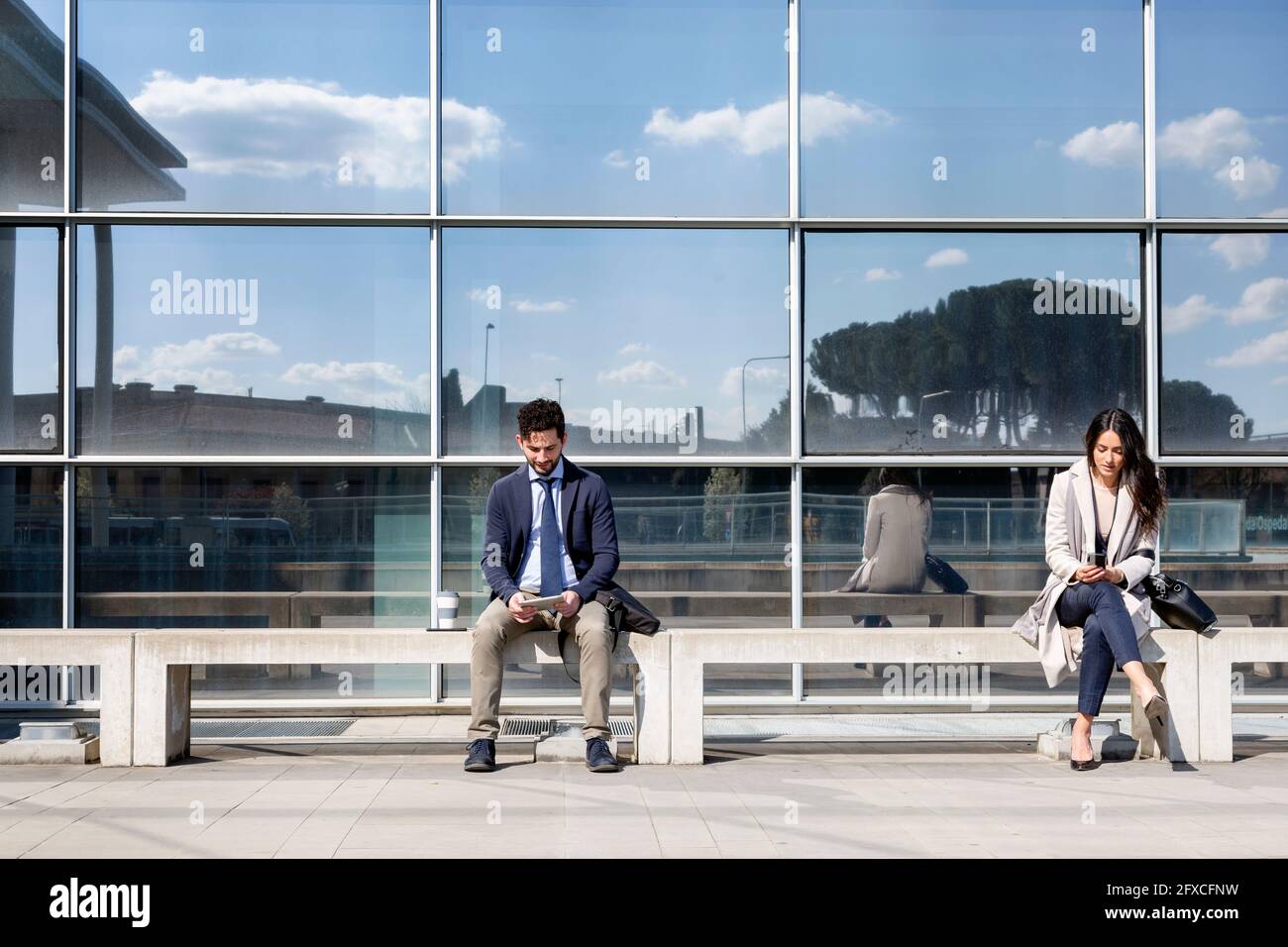 Business people sitting on bench in front of building Stock Photo - Alamy