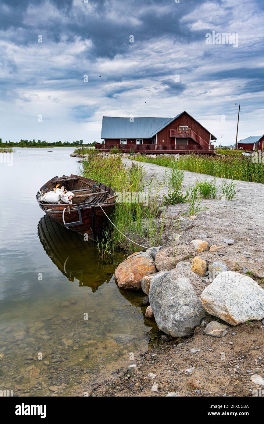 Finland, Rowboat moored along coast of Kvarken Archipelago with boathouse in background Stock Photo