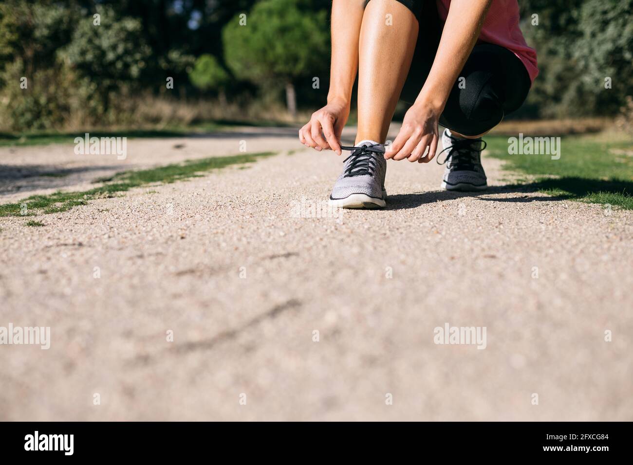Woman tying shoelace on footpath Stock Photo