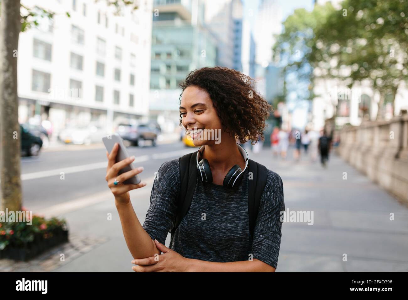 Smiling young woman looking at mobile phone in city Stock Photo