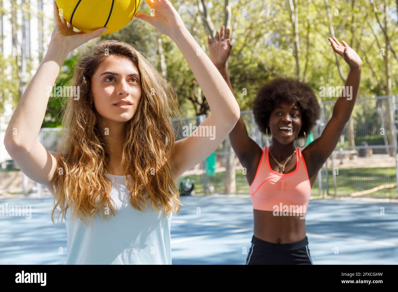 Young woman holding basketball with friend in background at park Stock ...