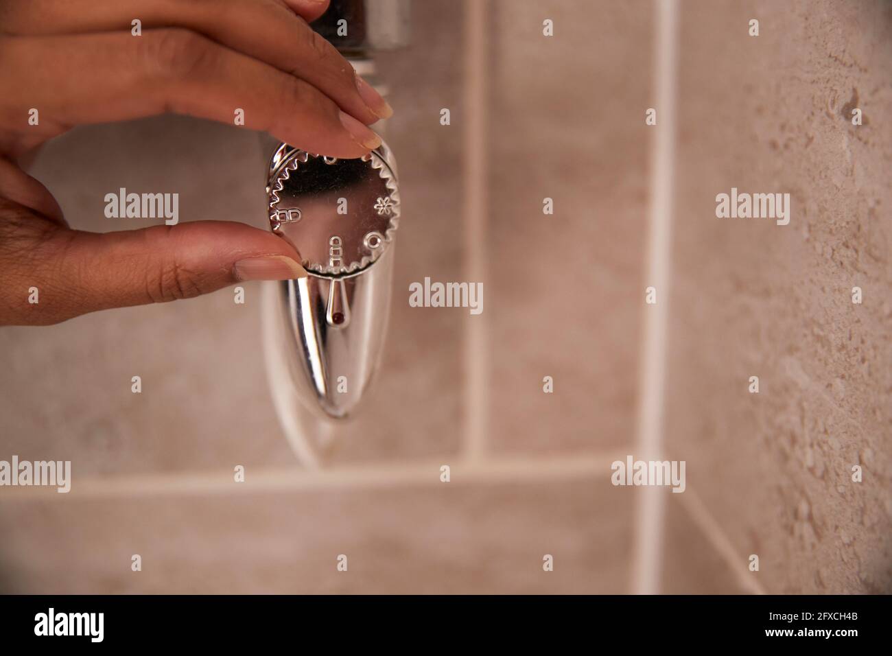 Woman holding faucet in bathroom Stock Photo