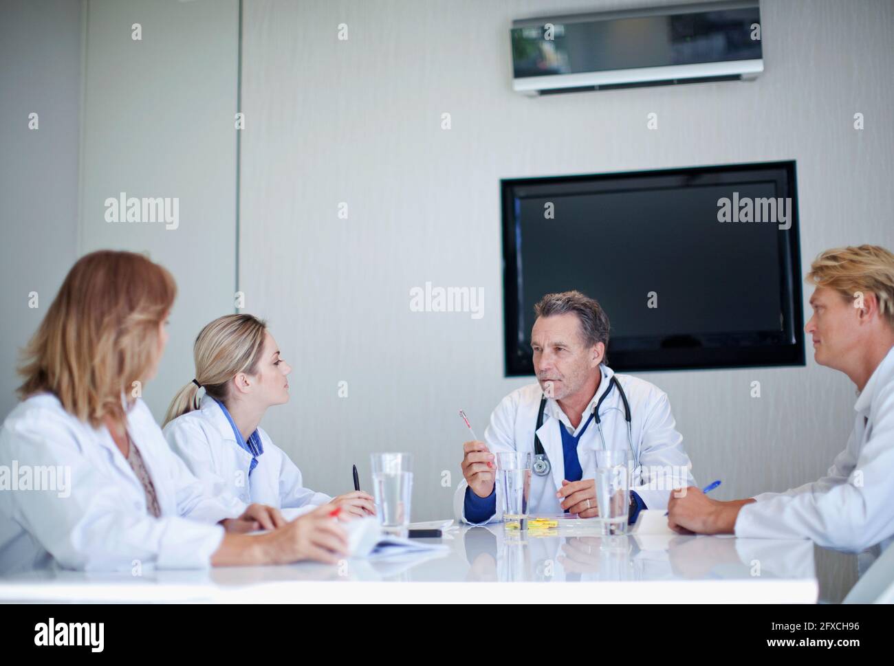 Senior doctor discussing with male and female healthcare workers during meeting in hospital Stock Photo
