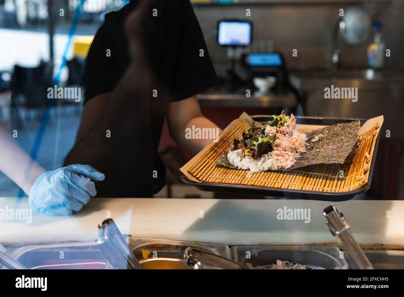 Waitress holding food tray by counter at restaurant Stock Photo