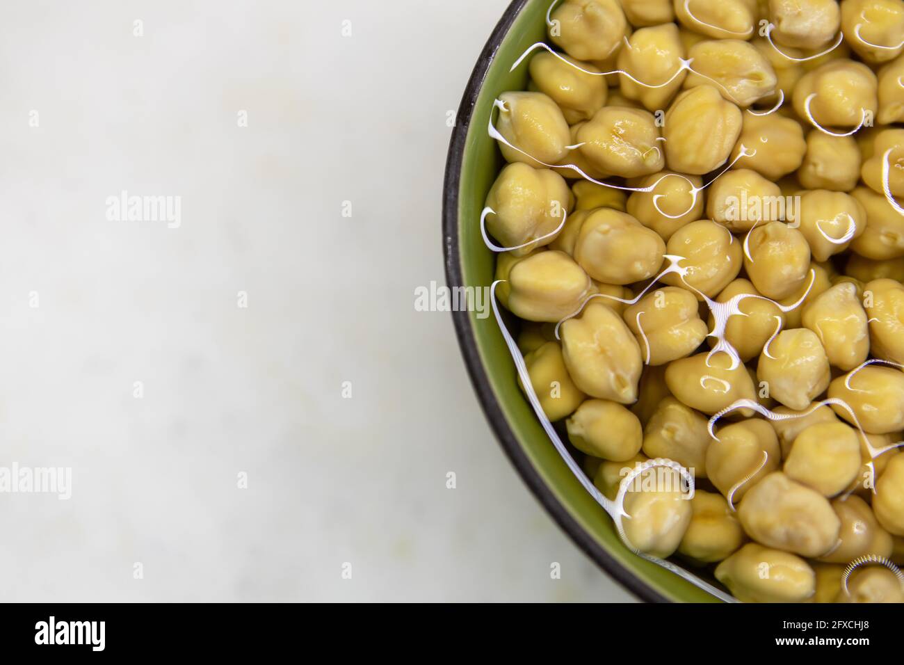 Chickpeas soaked in water, in bowl, on marble table. Concept of healthy eating, veganism, vegetarianism, meat and egg replacement. Prepare chickpeas b Stock Photo