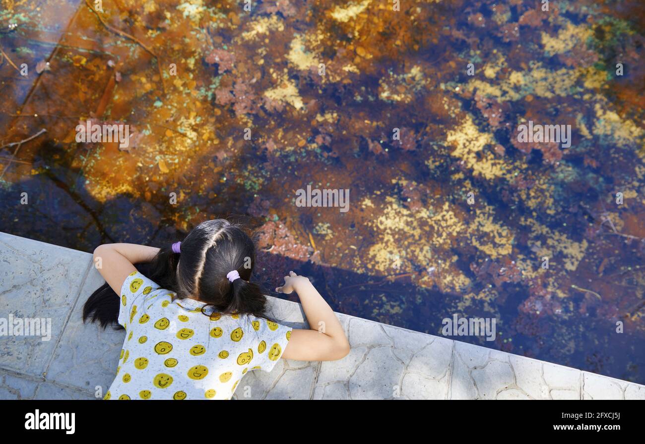 Curious girl looking in water while playing Stock Photo